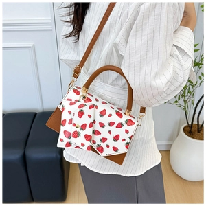Detail of strawberry print shoulder bag with brown leather strap and mini coin pouch