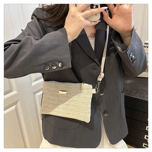 Detail of woven beige crossbody bag with gold metal plate and long shoulder strap