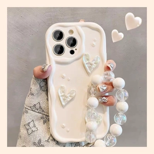 Detail of cream 3D wavy iPhone case with heart charms and pearl strap held in hand