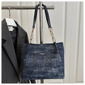 Detail of blue denim tote bag with leather gold chain strap and fashion logo patch