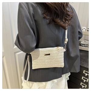 Close-up of beige woven texture shoulder bag with golden metal plate and crossbody strap