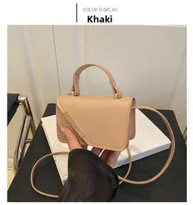 Detail of khaki leather mini bag with golden metal bar and round handle grip