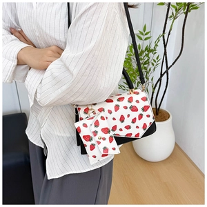 Detail of white strawberry print shoulder bag with gold clasp and small matching coin purse