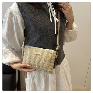 Detailed close-up of beige woven texture and metal logo on a stylish crossbody bag