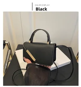Detail of black mini crossbody bag featuring a golden diagonal metal trim on the lid