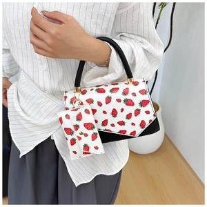 Detail of white strawberry print handbag with black braided handle and mini coin purse