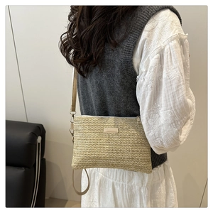 Detail of V-shaped woven texture on beige straw crossbody bag with leather strap
