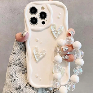 Detailed shot of wavy cream phone case with pearl heart charms and beaded hand strap