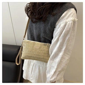 Detailed view of beige woven straw crossbody bag featuring dual straps on a model outfit