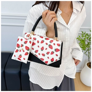 Detail of strawberry print handbag with matching small pouch and gold hardware accents