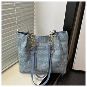 Detail of blue denim tote bag featuring sparkling rhinestones and gold chain handle