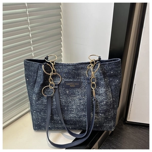 Detail of blue denim tote bag with silver rhinestones and gold chain strap connectors