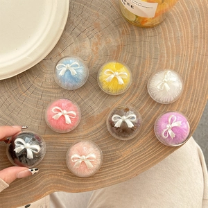 Bowknot faux fur ball phone grip socket in various colors on a wooden surface