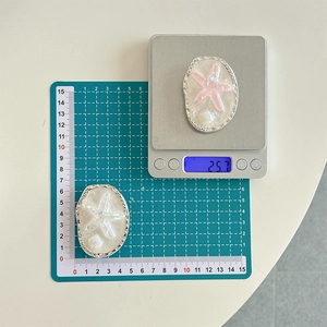 Detailed view of starfish resin phone stands showing dimensions and weight on a scale
