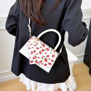 White textured crossbody bag with red strawberry print and matching coin purse charm
