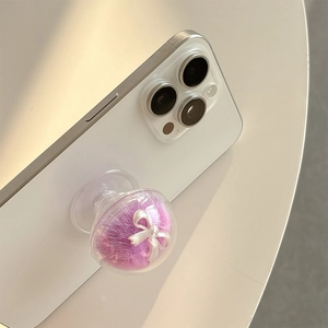 Detail of a purple faux fur phone socket with a silver bow on a white smartphone