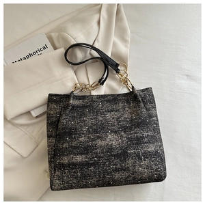 Detail of tweed tote bag with silver threads and gold-tone chain strap on white blazer