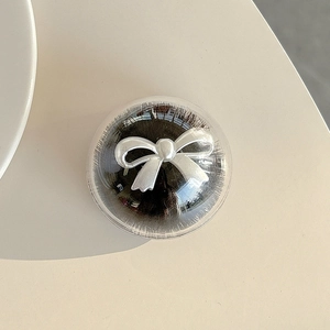 Close-up of a mink fur bow phone grip with a round clear shell and silver ribbon detail