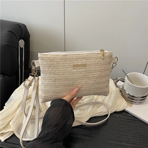 Chic beige woven crossbody bag with gold hardware and adjustable strap shown in hand
