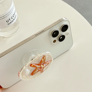 Creative orange starfish pop-socket with glitter epoxy on a white smartphone