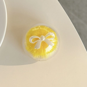 Detail of round yellow faux fur phone grip featuring a pearly white bow decoration