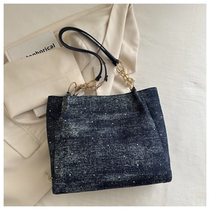 Detailed view of dark blue denim tote bag with silver beads and gold chain strap