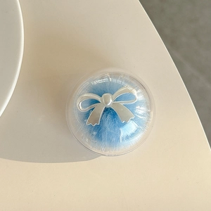 Detail of clear round cosmetic puff case with silver bow and blue plush puff inside