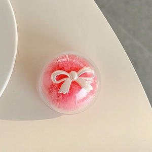 Detail of round phone grip featuring a fluffy pink mink fur ball and white pearly bow