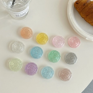Variety of colorful glitter phone griptoks scattered on white table in a cafe setting