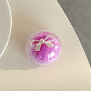 Detail of round purple faux fur phone grip with a white pearl-finish ribbon bow decoration