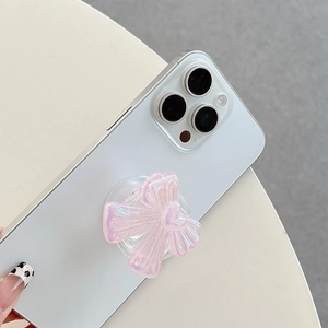Close-up of a stylish iridescent pink bow phone socket grip attached to a white phone