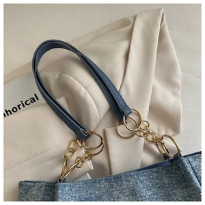 Detail of blue denim tote bag with silver glitter finish and gold chain shoulder strap