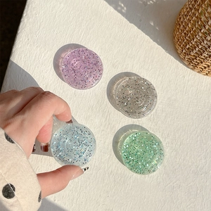 Close-up of four glittery resin phone grips in purple, silver, blue, and green shades
