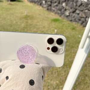 Macro detail of round purple glitter phone grip stand with shimmering sequins on white phone