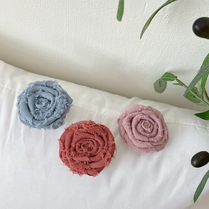 Detail of fabric rose phone grips in blue, red, and pink with vintage frayed petal edges
