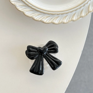 Detailed view of a glossy black bow phone socket with heart detail on white surface.