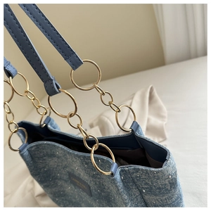 Blue denim tote bag detail featuring rhinestone studs and gold ring chain strap