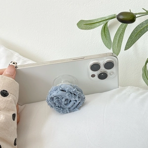 Detail of blue denim fabric flower phone grip with vintage frayed edges on white phone