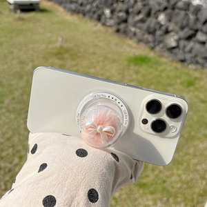 Close-up of pink faux fur phone grip with pearl bow on white smartphone back