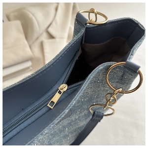 Detailed shot of golden zipper and sparkling blue denim texture on large tote bag