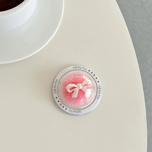 Macro detail of a pink plush ball phone grip with a white bow in Gift For You packaging