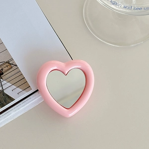 Close-up of pink heart-shaped expandable phone socket with mirror on a soft background