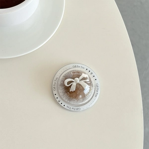 Macro view of clear spherical phone grip featuring a brown core and a white resin bow accent