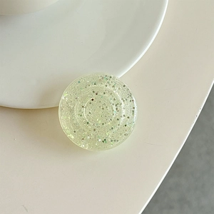 Close-up of a translucent light green phone grip with colorful sparkling glitter inside