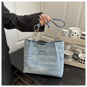 Detailed shot of denim tote bag with shimmering sequins and gold chunky chain handle