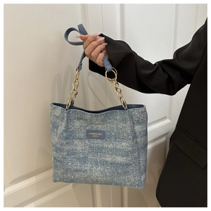 Detail of light blue denim tote bag featuring small rhinestones and chain strap handles