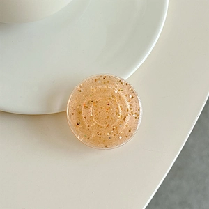 Macro shot of amber resin phone grip with glitter gold flakes on a minimalist ceramic plate