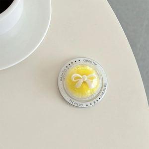 Macro view of transparent round phone grip with yellow plush center and white bow detail