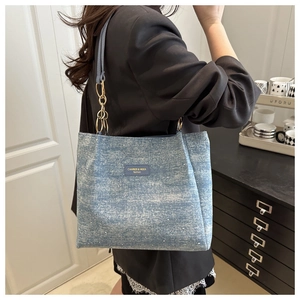 Detail of light blue denim tote bag with gold chain strap and shimmering crystal accents