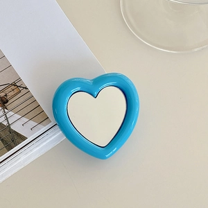 Close-up of a heart-shaped blue phone socket stand with an integrated silver mirror surface